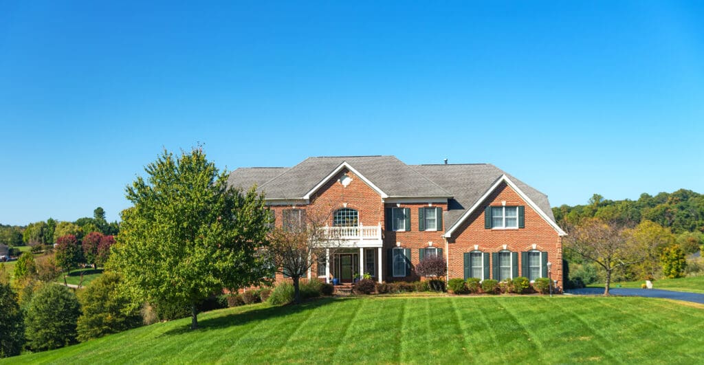 Large brick house with a large green lawn.